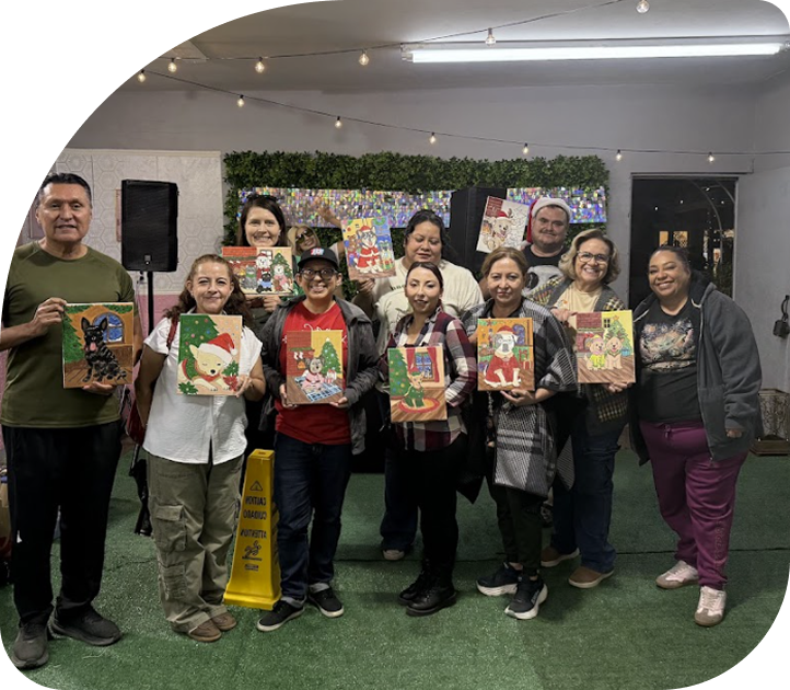 Workshop participants holding completed paintings during a community art experience