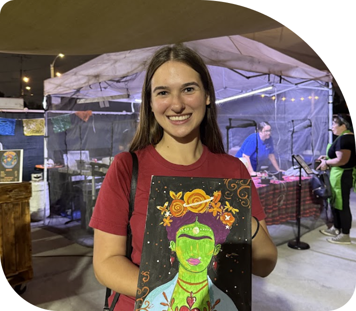 Participant holding a colorful painted canvas during a creative community event